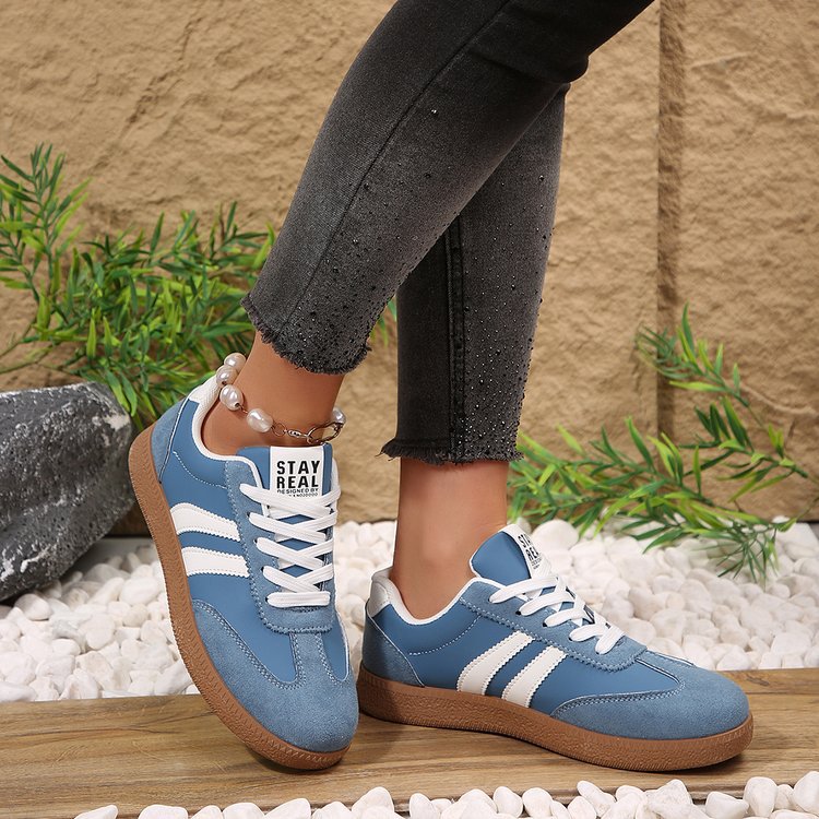 Blue sneakers with white stripes worn by a person on a natural background