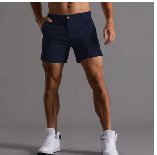 Person wearing navy shorts and white sneakers on a gray background