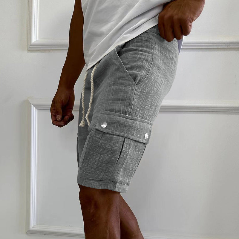Person wearing gray cargo shorts with a white shirt against a light-colored wall.