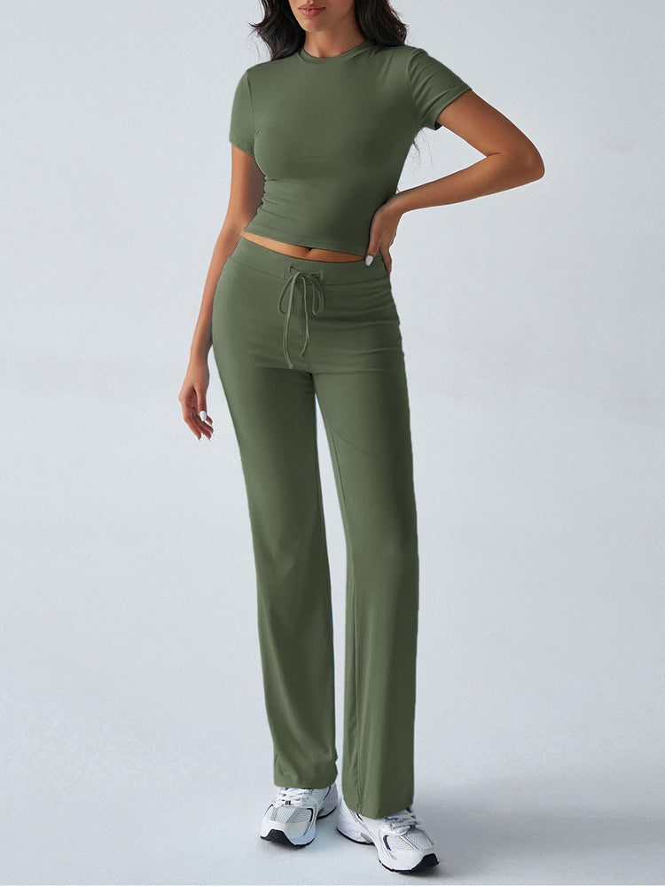 Woman wearing a green outfit with a top and pants on a light gray background