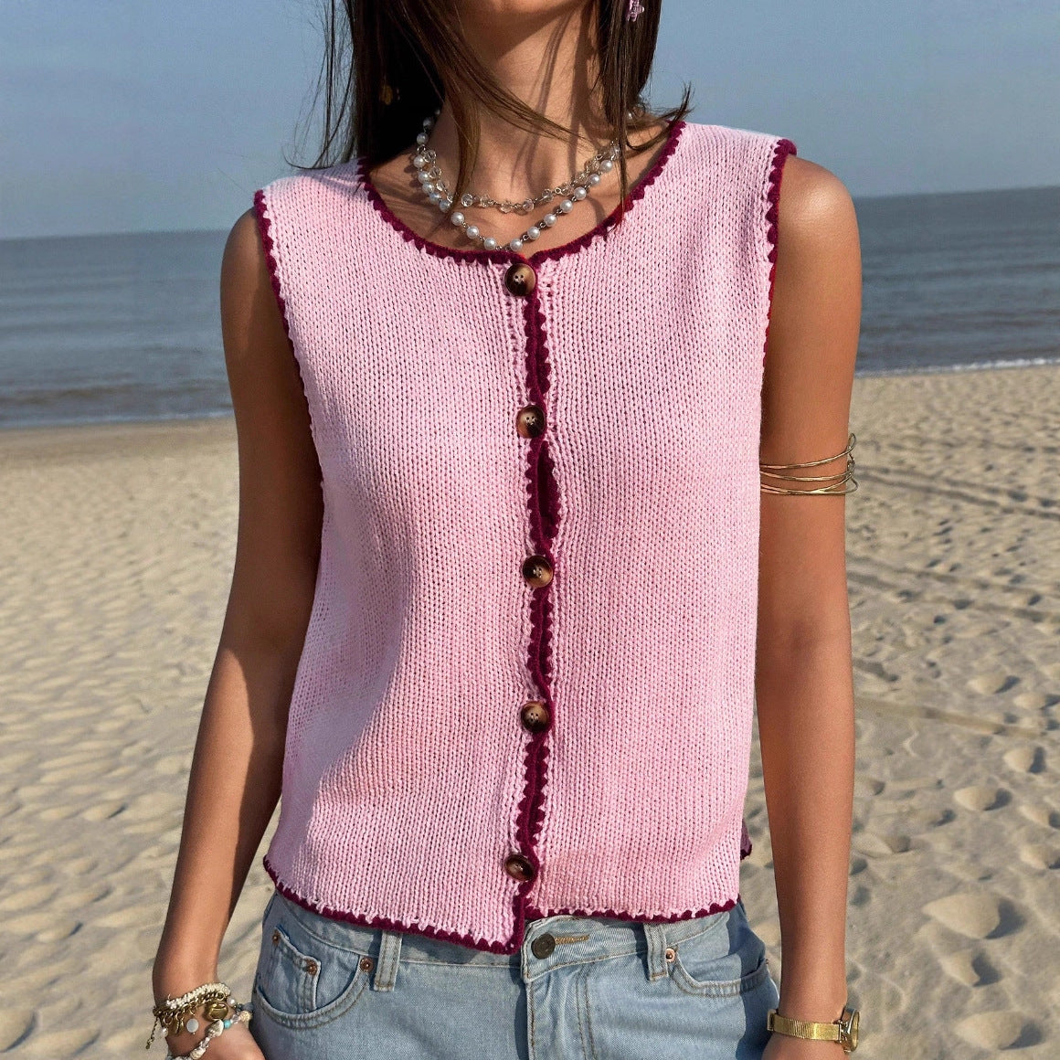 Woman wearing a pink knitted vest on a beach