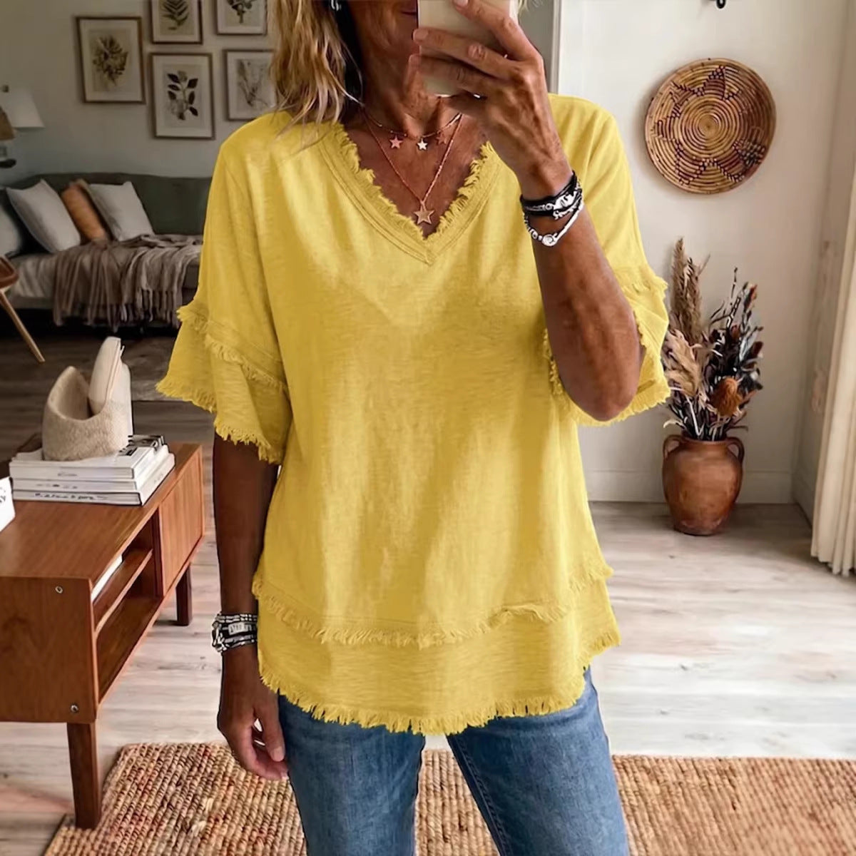 Person wearing a yellow top and blue jeans in a living room setting.