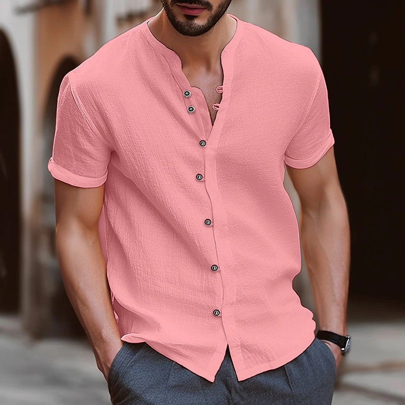 Man wearing a pink short-sleeve button-up shirt with a blurred background