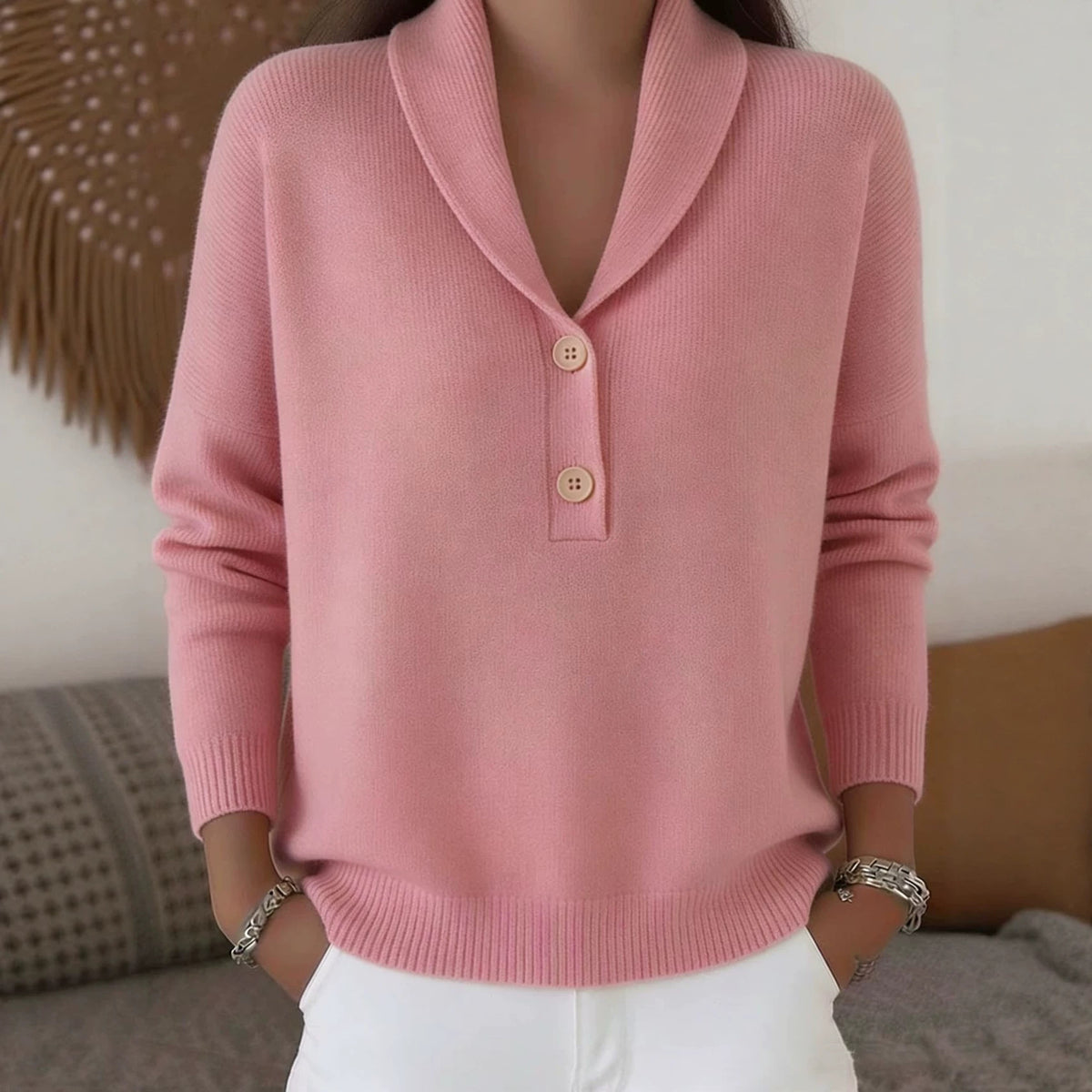 Person wearing a pink sweater with button details in a casual setting