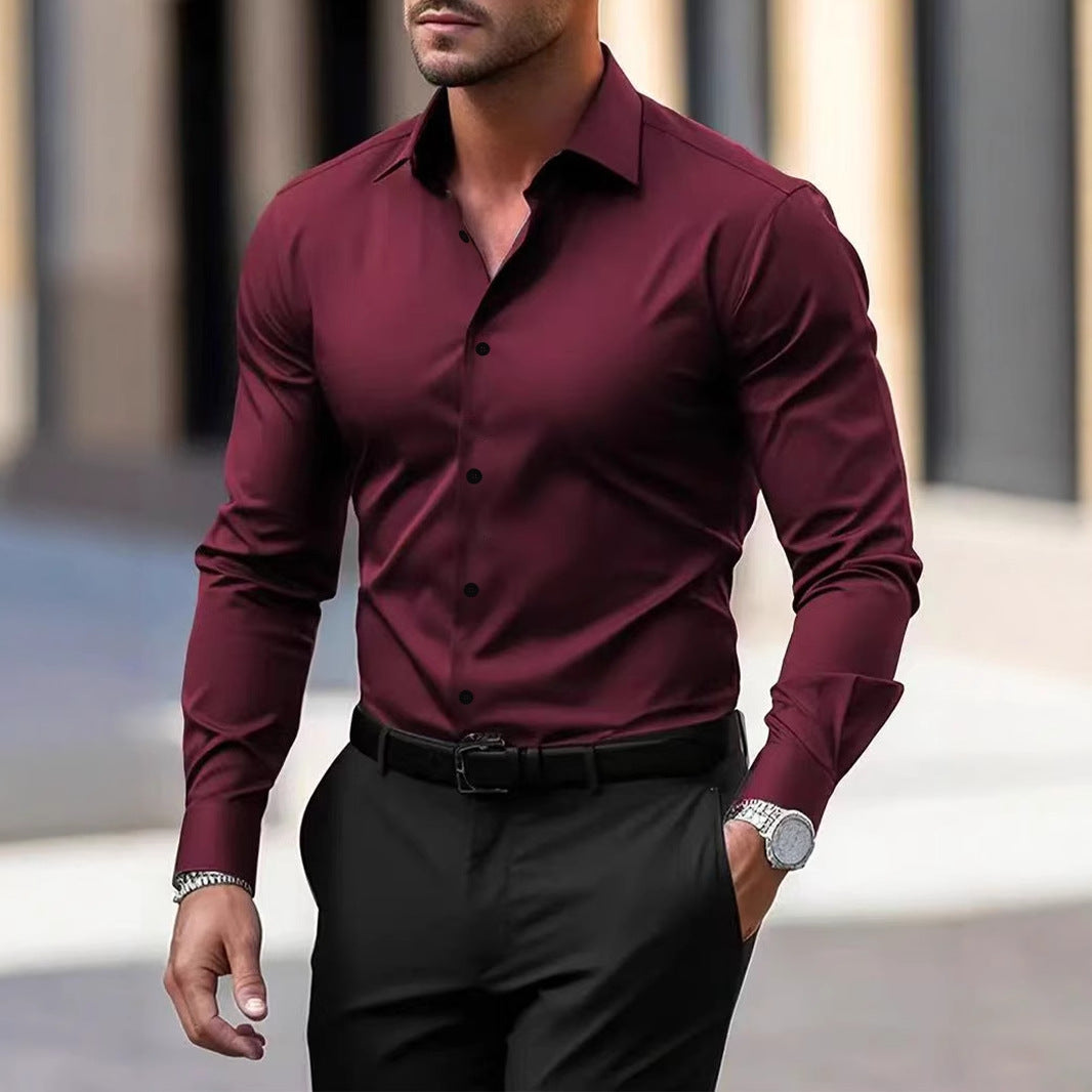 Man wearing a burgundy dress shirt and black pants with a blurred background
