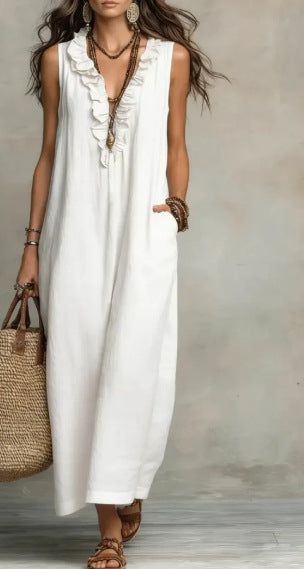 Woman wearing a white sleeveless dress with ruffled details, holding a straw bag against a neutral background.