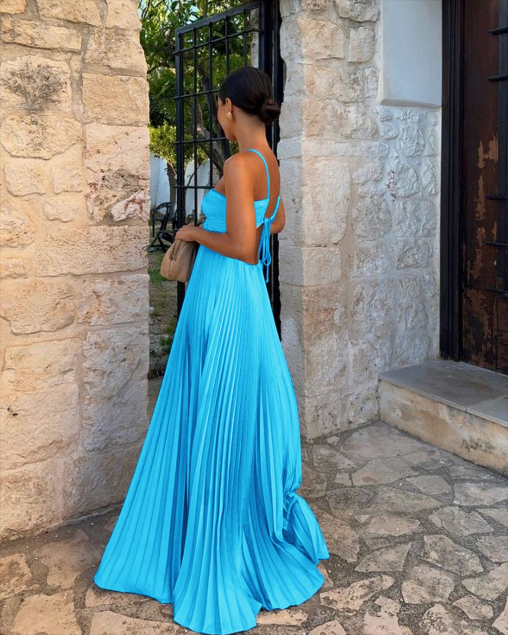 Woman in a blue dress standing outside a stone building.
