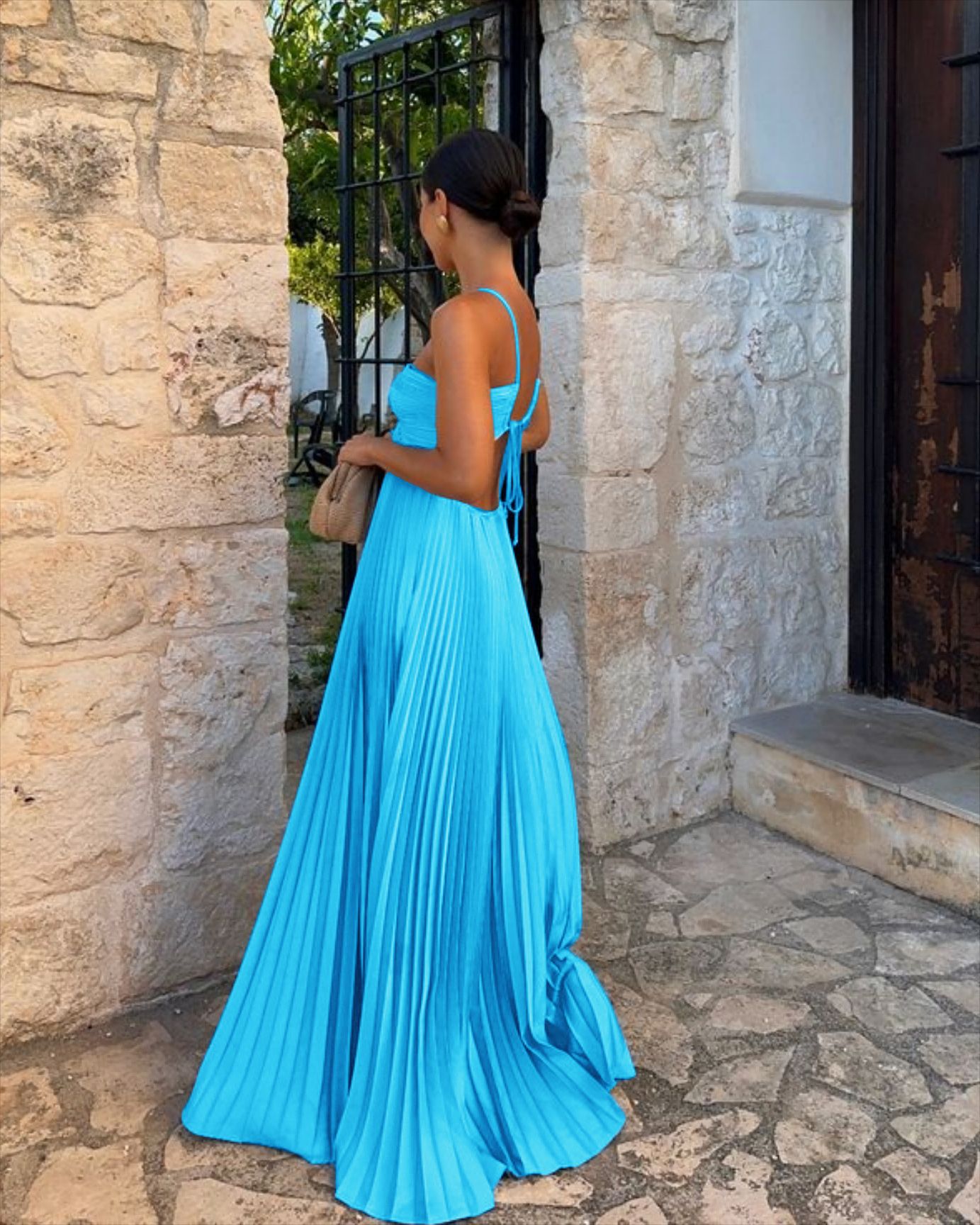 Woman in a blue dress standing outside a stone building.