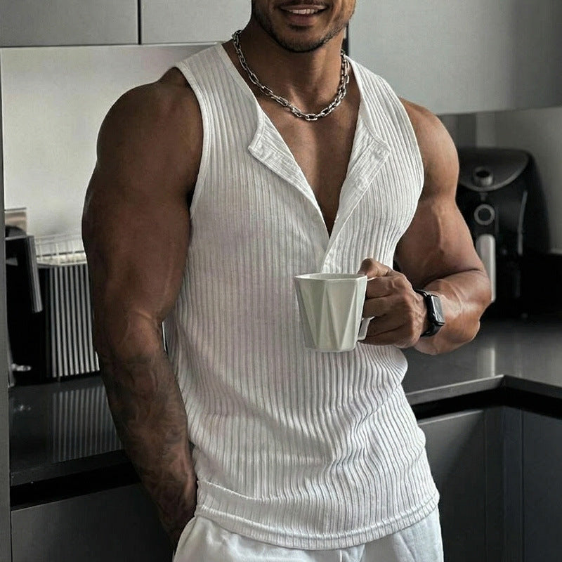 Man in a white tank top holding a white cup in a kitchen.