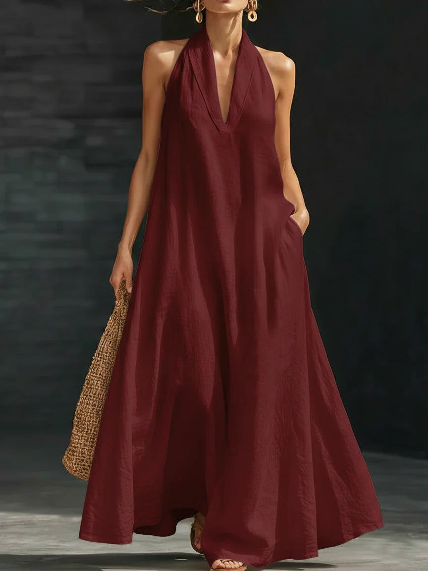 Woman wearing a burgundy halter neck dress against a dark background