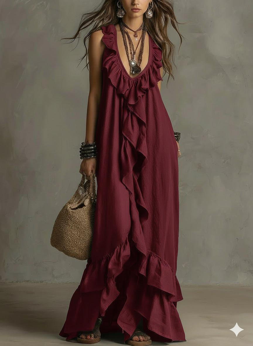 Woman wearing a burgundy ruffled dress holding a textured handbag against a neutral background