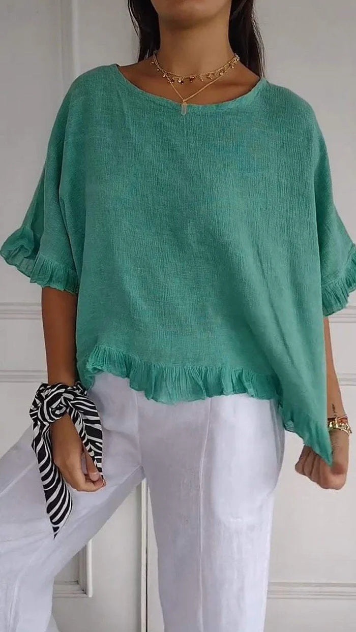 Person wearing a green top and white pants with a neutral background