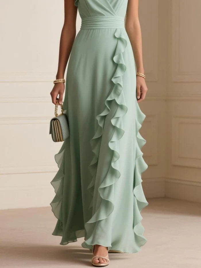 Woman wearing a light green ruffled dress holding a clutch in an indoor setting.