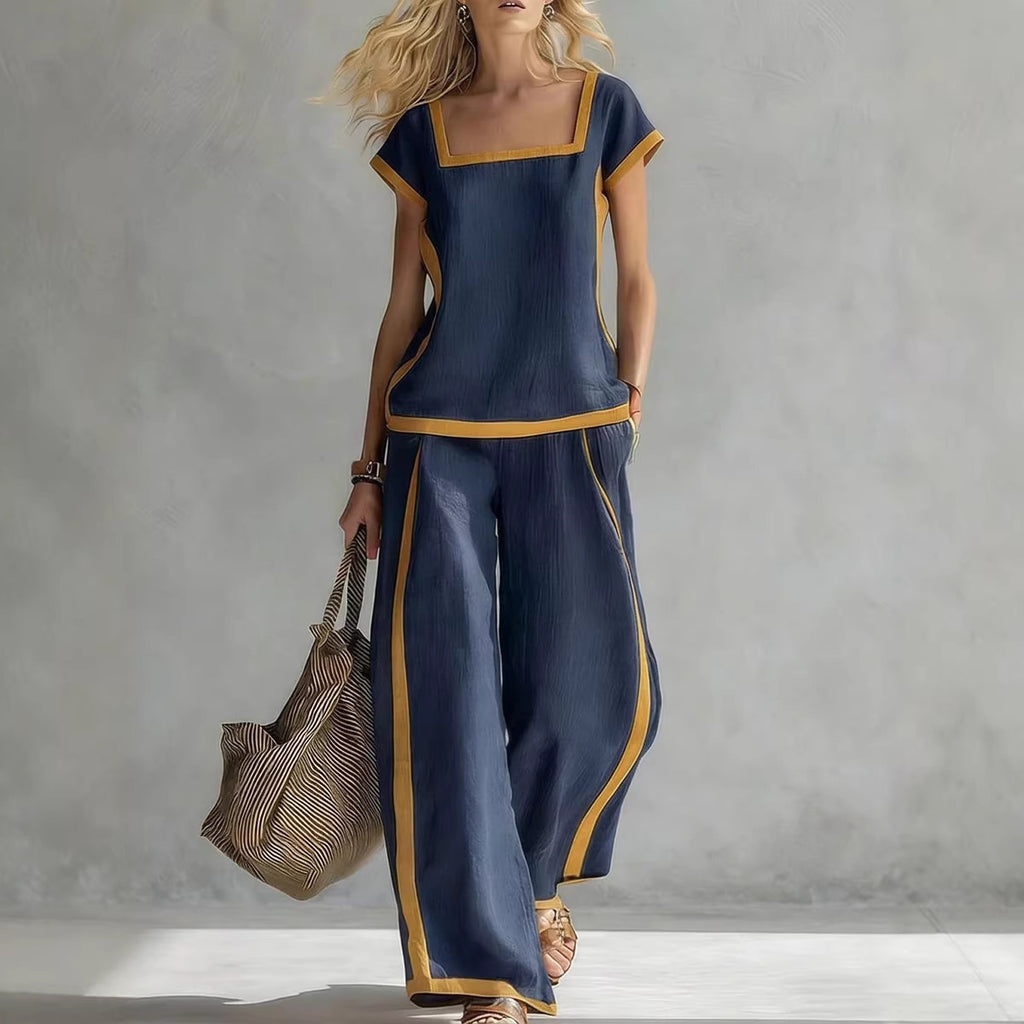 Woman wearing a blue outfit with gold trim holding a bag against a gray background