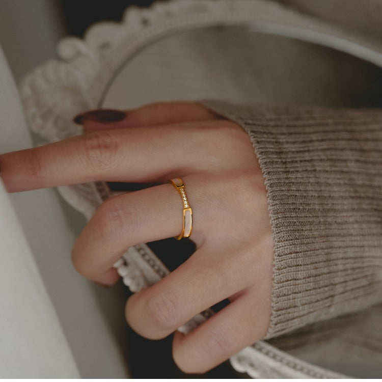 Close-up of a hand wearing a gold ring with a blurred background