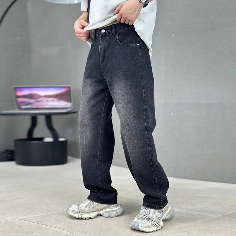 Person wearing dark jeans and white sneakers in a studio setting with a computer screen in the background.