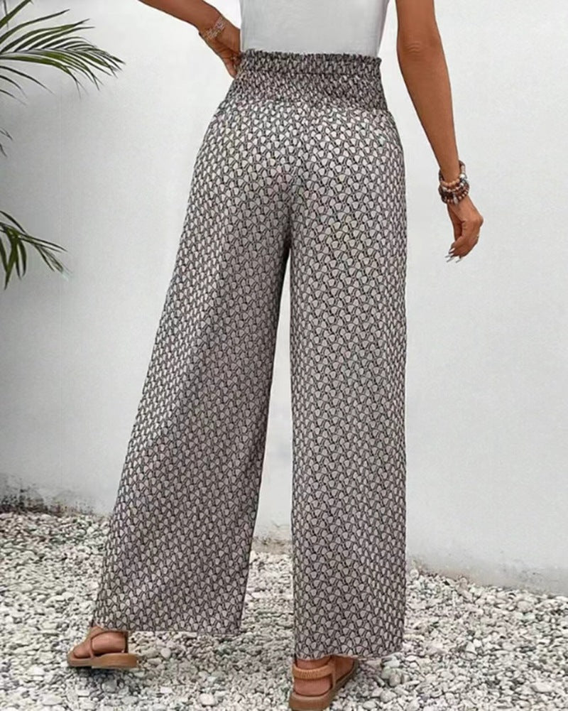 Person wearing patterned wide-leg pants against a white wall.