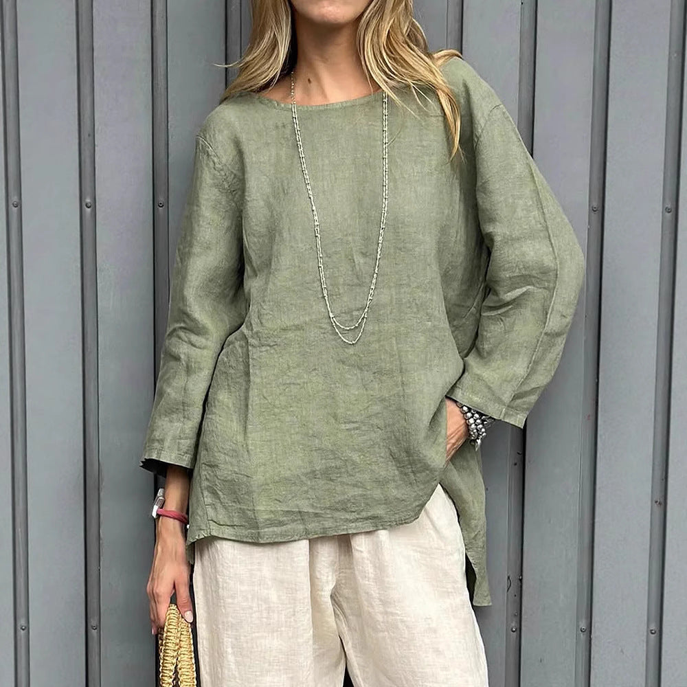 Woman wearing a green linen top and white pants against a gray background