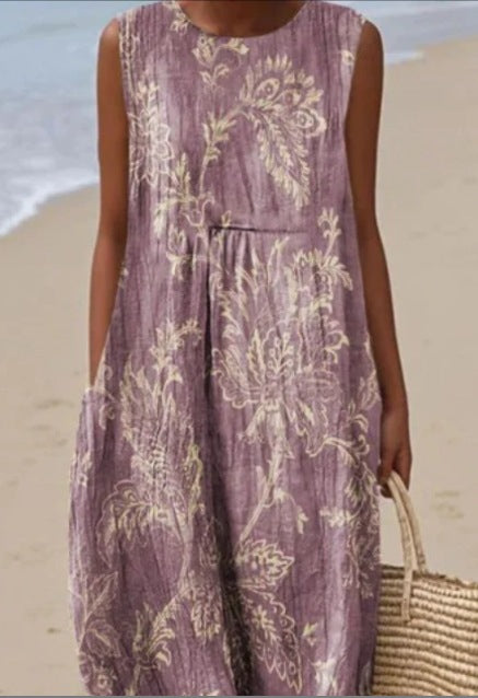 Woman wearing a purple floral dress on a beach.