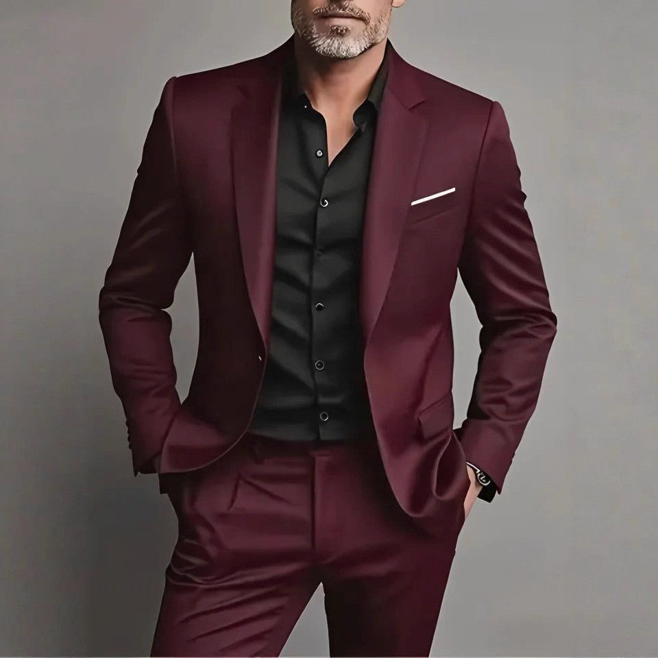 Man wearing a burgundy suit with a black shirt against a gray background