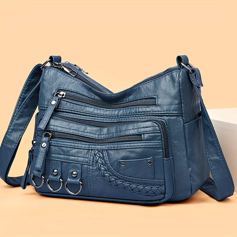 Blue leather handbag with multiple pockets and straps on a beige background