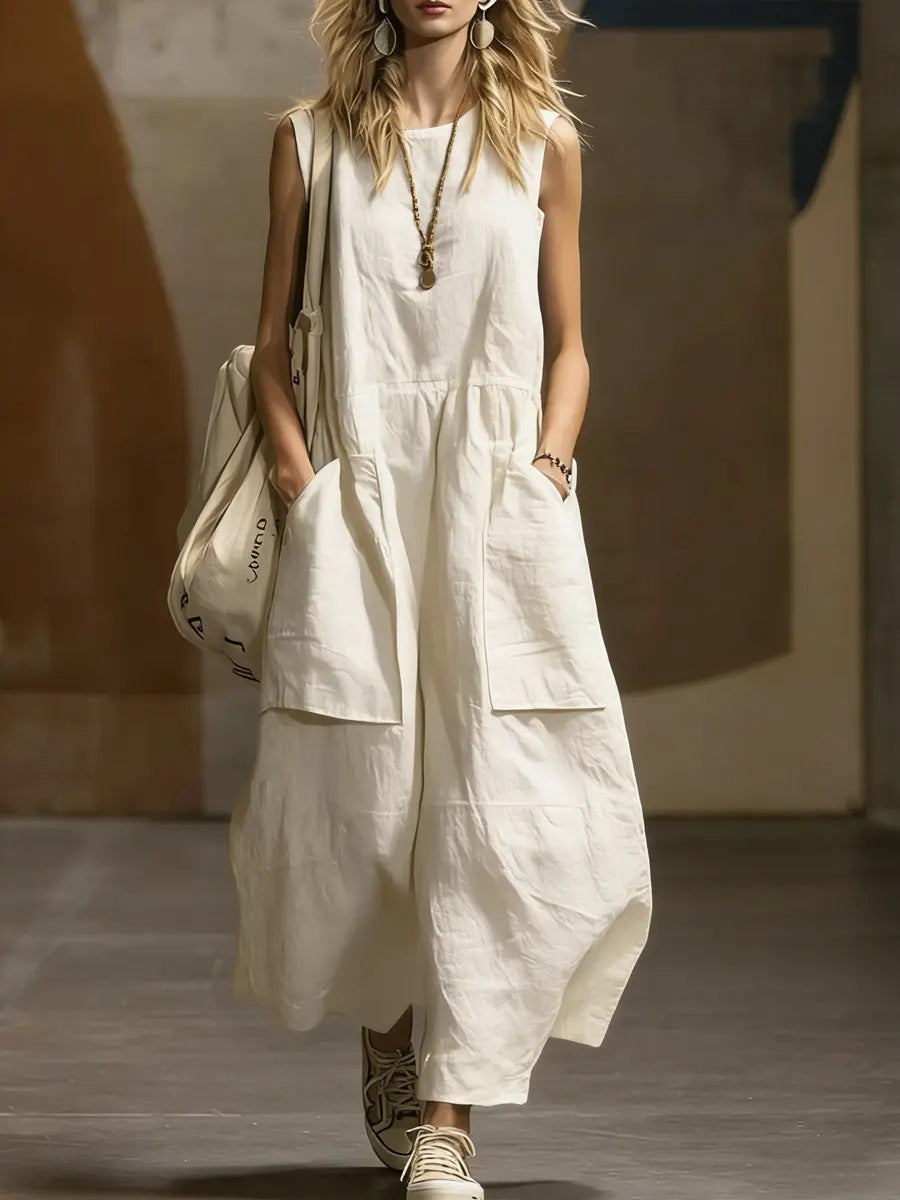 Woman wearing a white sleeveless dress with wide-leg pants, holding a matching bag.