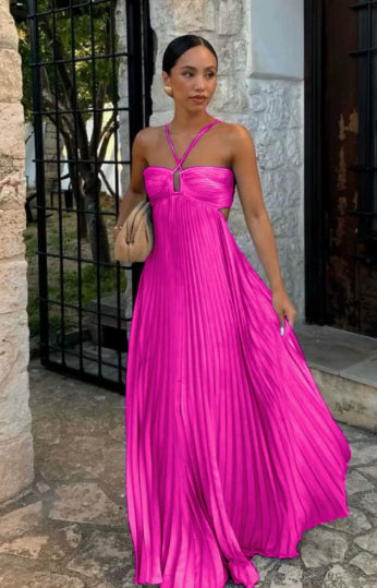 Woman in a pink pleated dress standing outdoors.