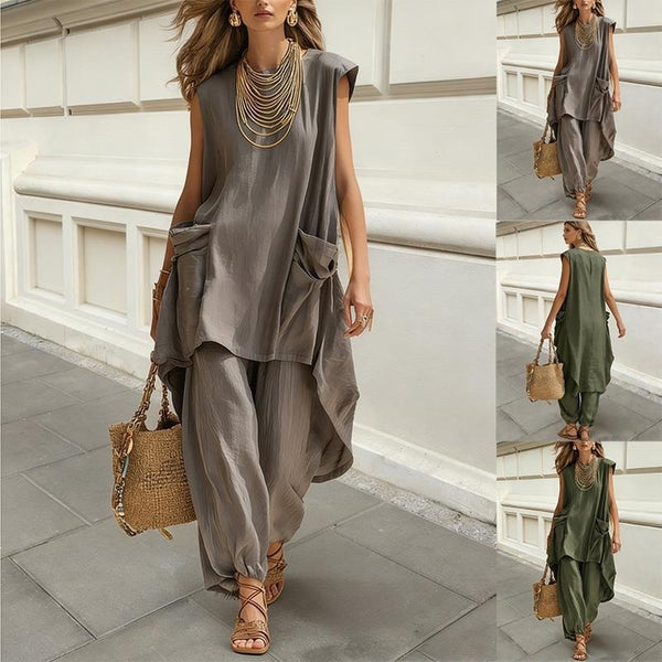 Woman wearing a gray outfit with wide-leg pants and a brown bag, standing on a stone pavement.