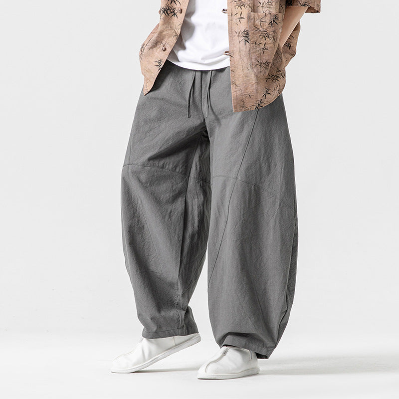 Person wearing gray wide-leg pants with a plain background