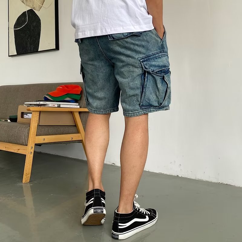 Person wearing blue denim shorts and black sneakers in a room with a couch and colorful items.