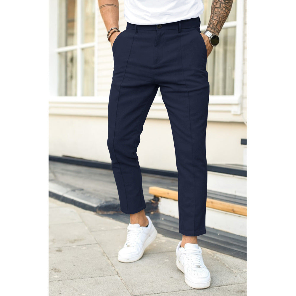 Person wearing navy pants and white sneakers standing on a sidewalk.