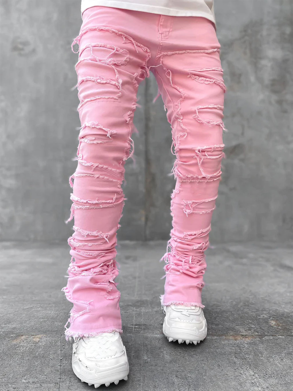 Pink distressed jeans worn by a person on a gray background