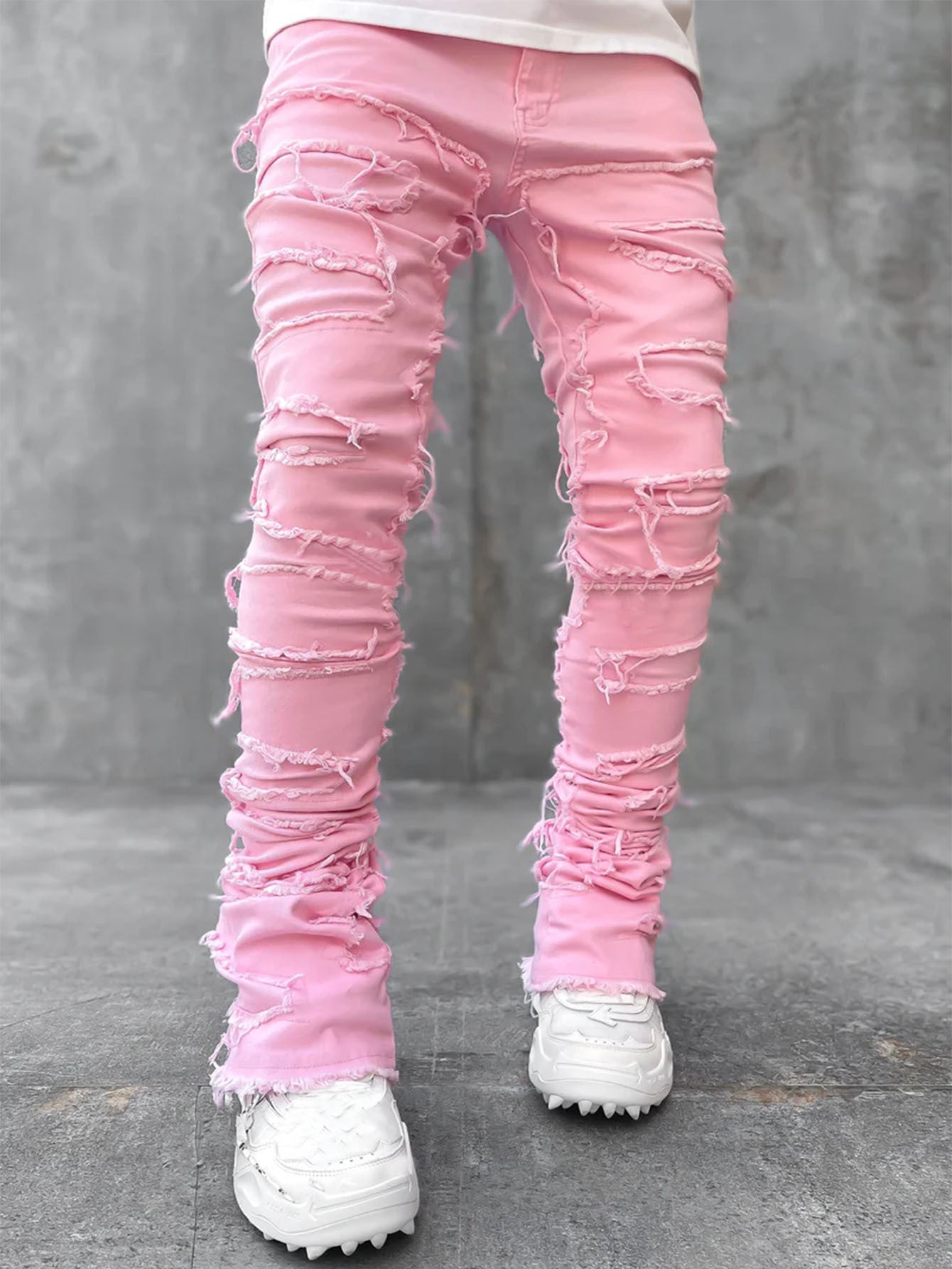 Pink distressed jeans worn by a person on a gray background
