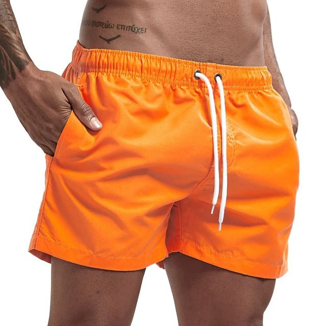 Orange swim shorts with a white drawstring on a white background