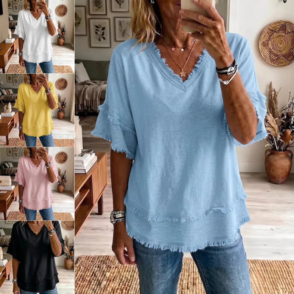 Woman wearing a blue frayed hem top in a home setting.