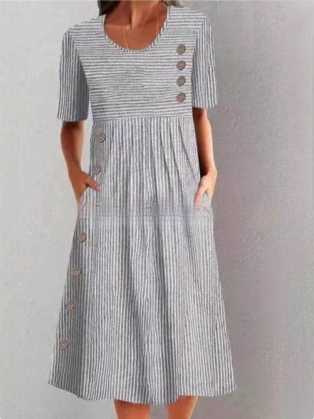 Woman wearing a striped dress with buttons on a plain background