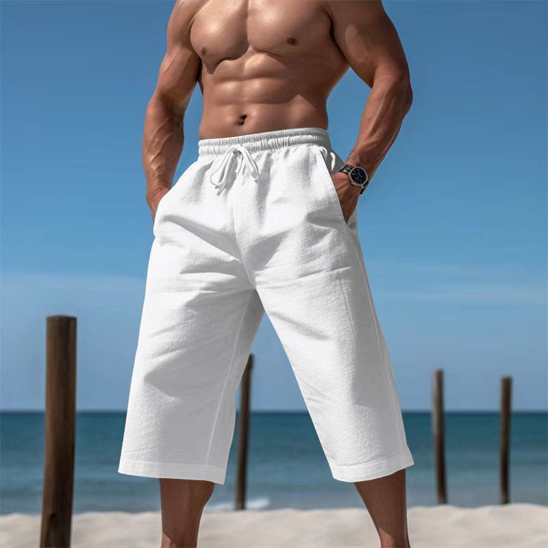 Man wearing white shorts on a beach with clear blue sky and ocean.