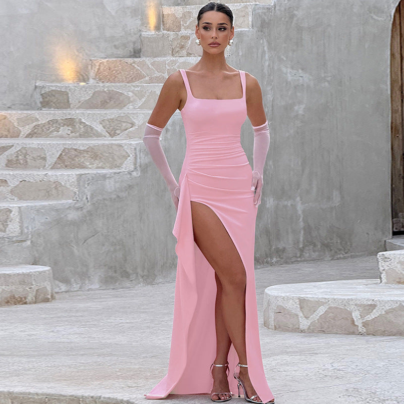 Woman in a pink evening gown with a high slit standing on stone steps.