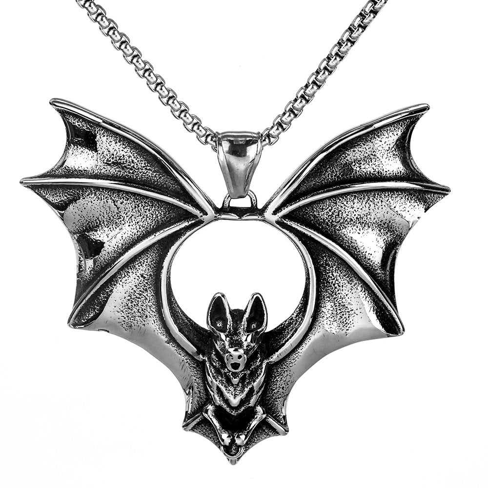 A silver-toned metal bat pendant necklace with wings spread, featuring a small bat figure in the center and a matching chain against a plain white background.