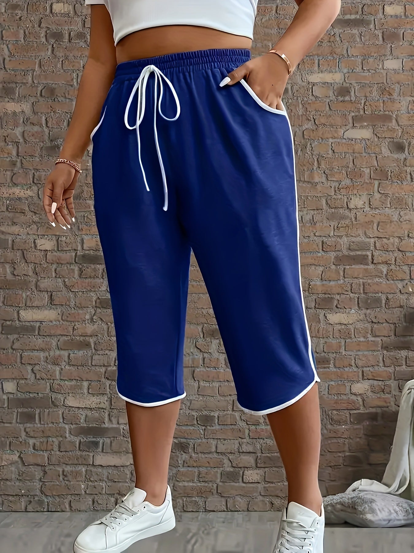 Person wearing blue shorts with white drawstring and trim against a brick wall.