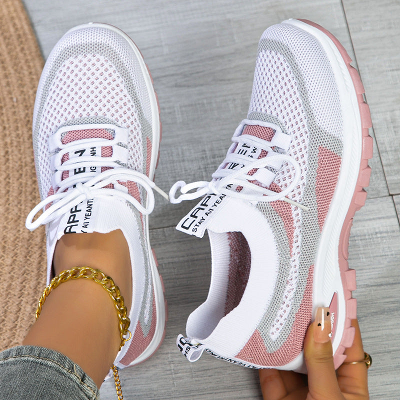 White and pink sneakers with visible branding on a wooden floor.