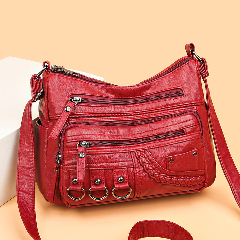 Red leather handbag with multiple pockets and straps on a beige background