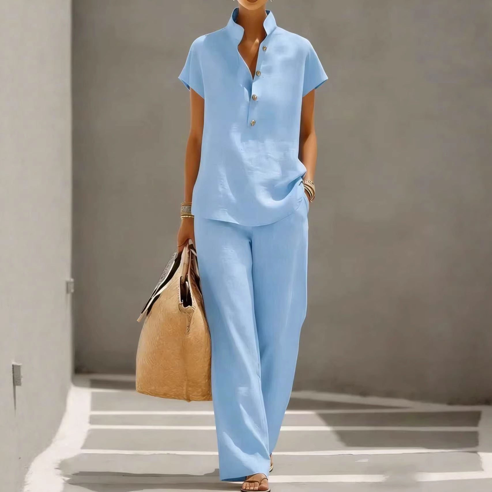Person wearing a light blue outfit holding a beige bag against a neutral background