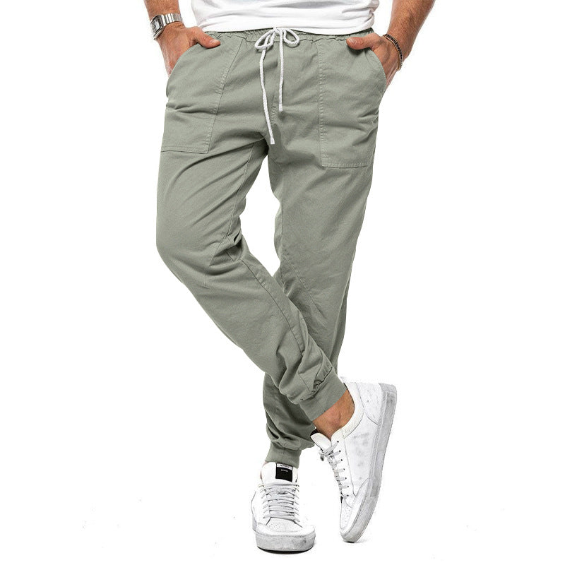 Person wearing light gray jogger pants and white sneakers on a white background