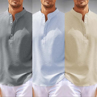 Three men wearing different colored shirts with a plain background