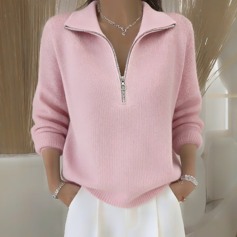 Person wearing a pink zip-up sweater with a neutral background
