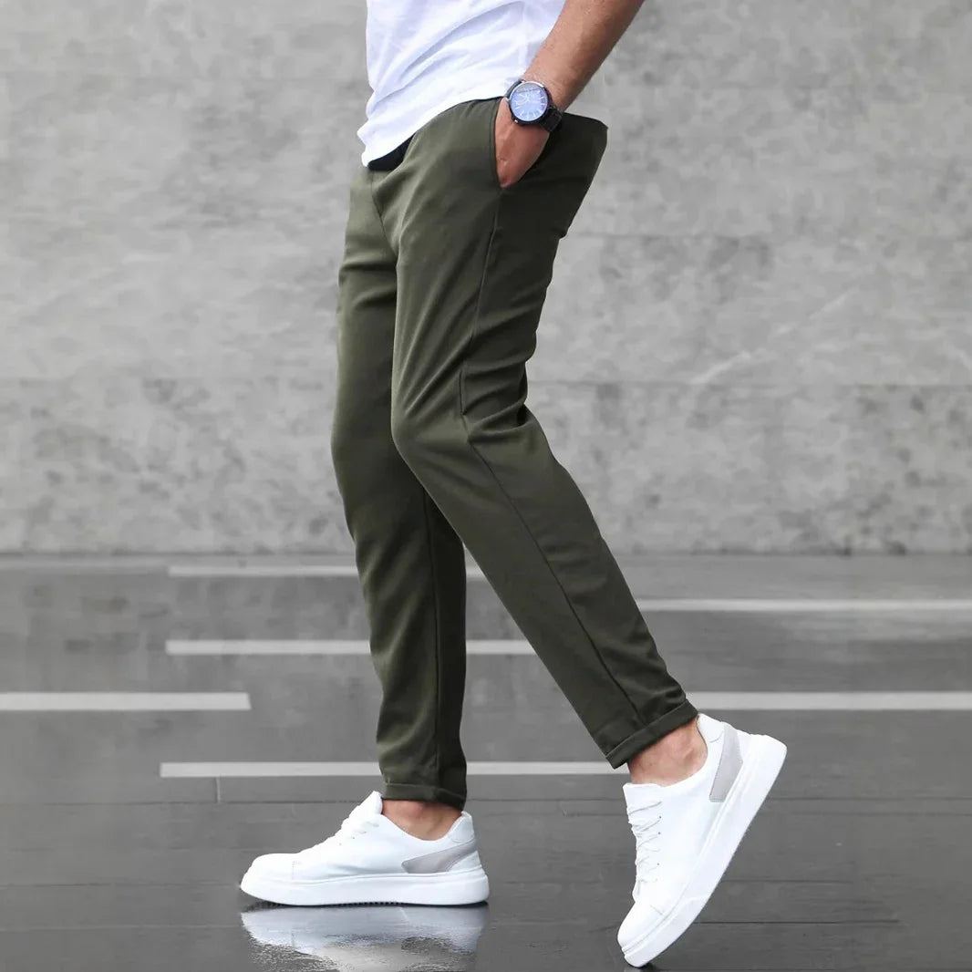 Person wearing olive green pants and white sneakers on a gray background