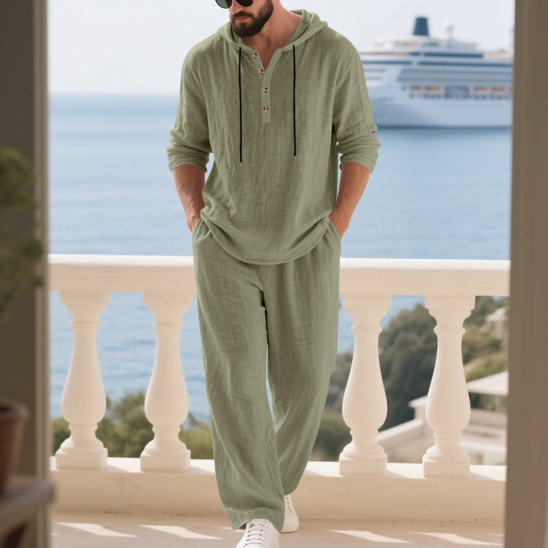 Man wearing a green hoodie and pants on a balcony with ocean and cruise ship in the background