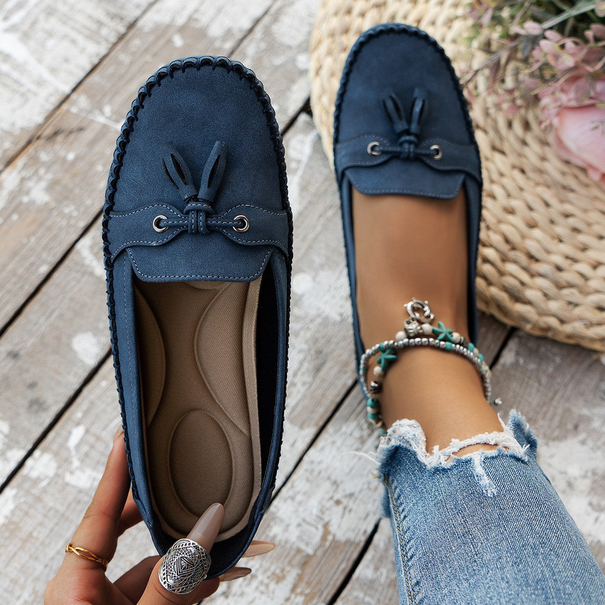 Blue loafers with tassels on a wooden floor