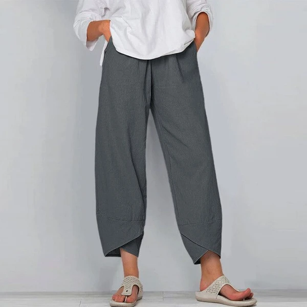 Person wearing gray wide-leg pants and a white top against a plain background